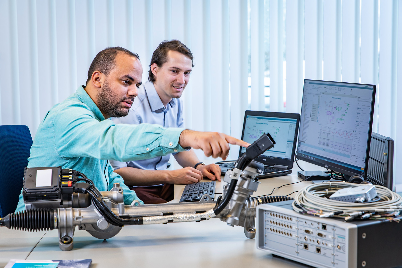 two engineers work at a desk performing the blend of test and simulation that is called model-based system testing
