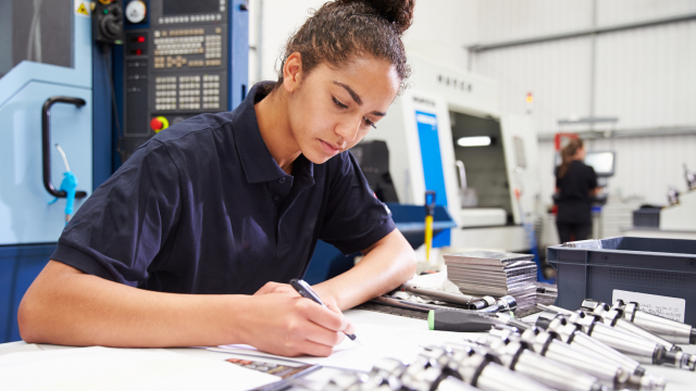 A woman studies some documents in an engineering environment.