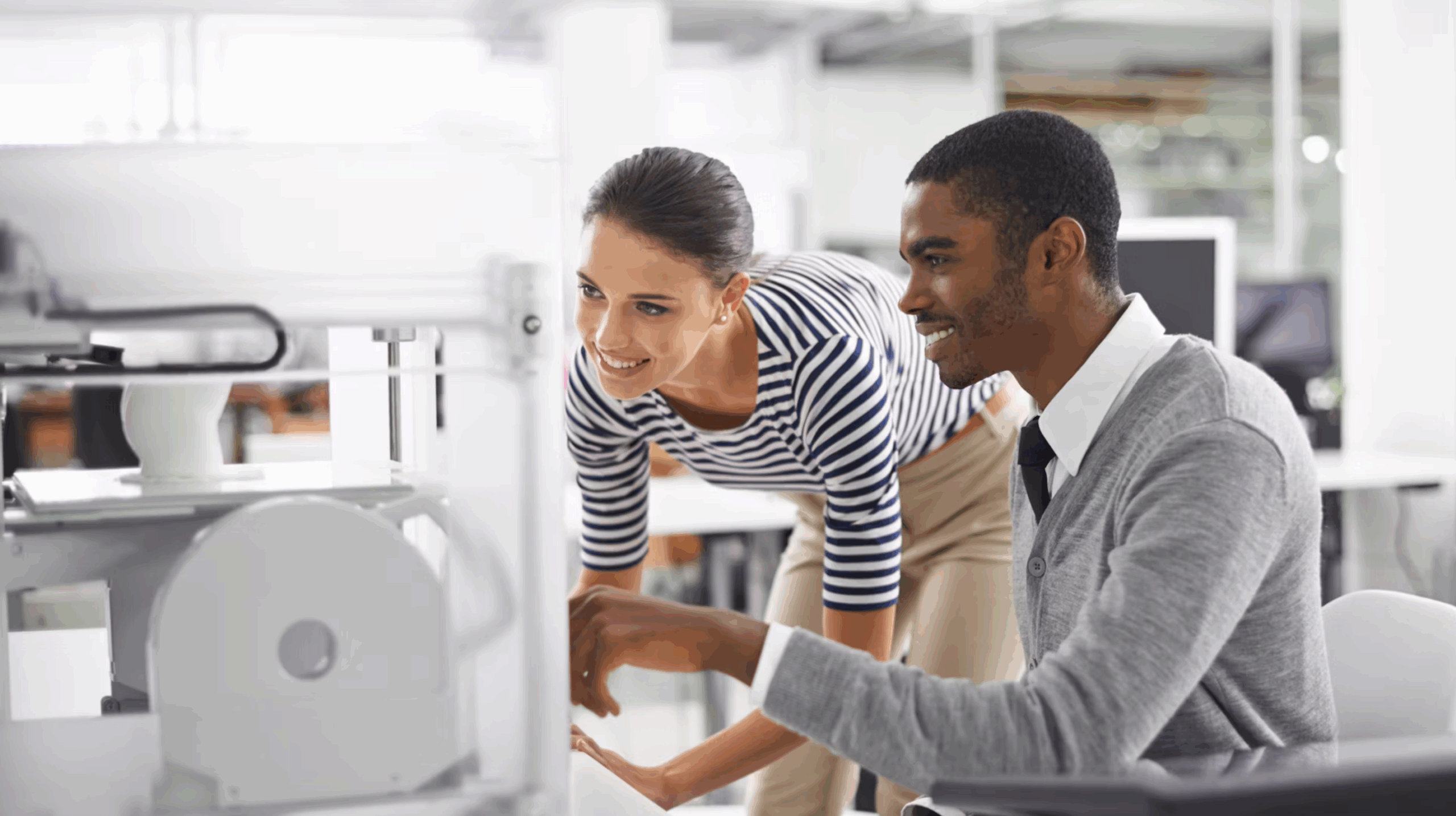 Two young engineers work on a computer together.