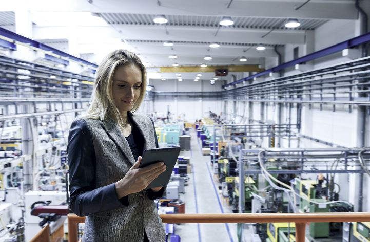 Woman performing product serviceability analysis on a tablet above a manufacturing plant floor
