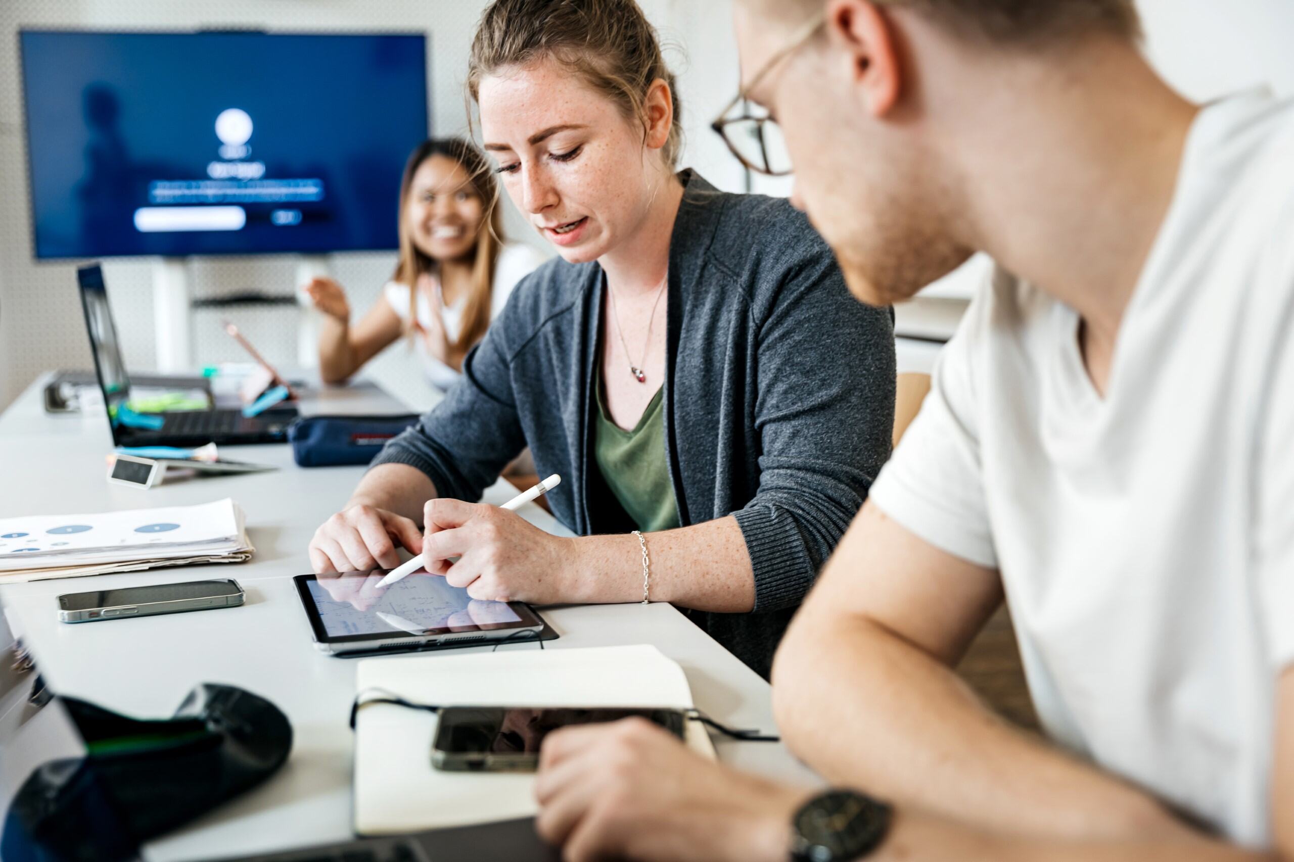 Office worker looking at a tablet and explaining a design to a colleague sitting next to them