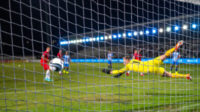 Soccer goalkeeper jumping and catching ball during sports match