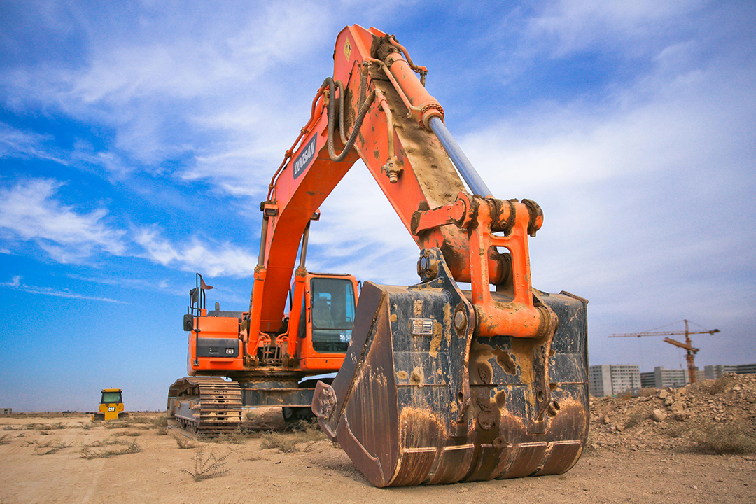 Image of an excavator, an example of a machine produced by heavy equipment manufacturers, on a construction site.