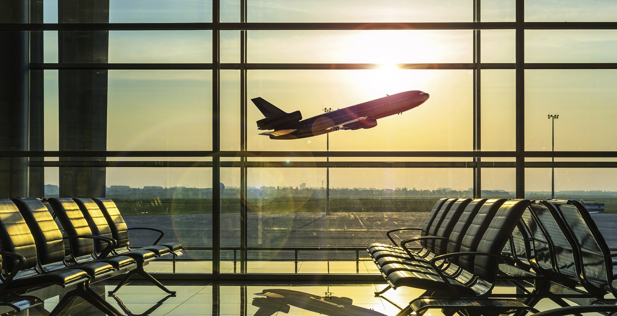 Airplane taking off outside an airport's departure lounge.