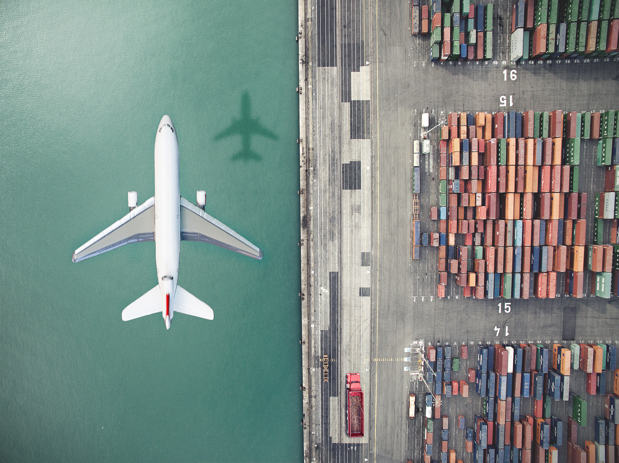 An airplane flying over a container port.