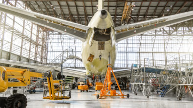 A rear-view of a passenger aircraft undergoing maintenance in a hangar.