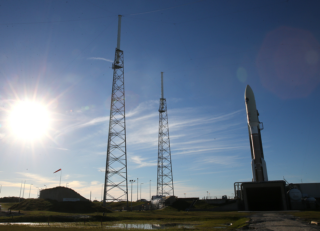 A rocket standing on a launchpad as the sun rises.