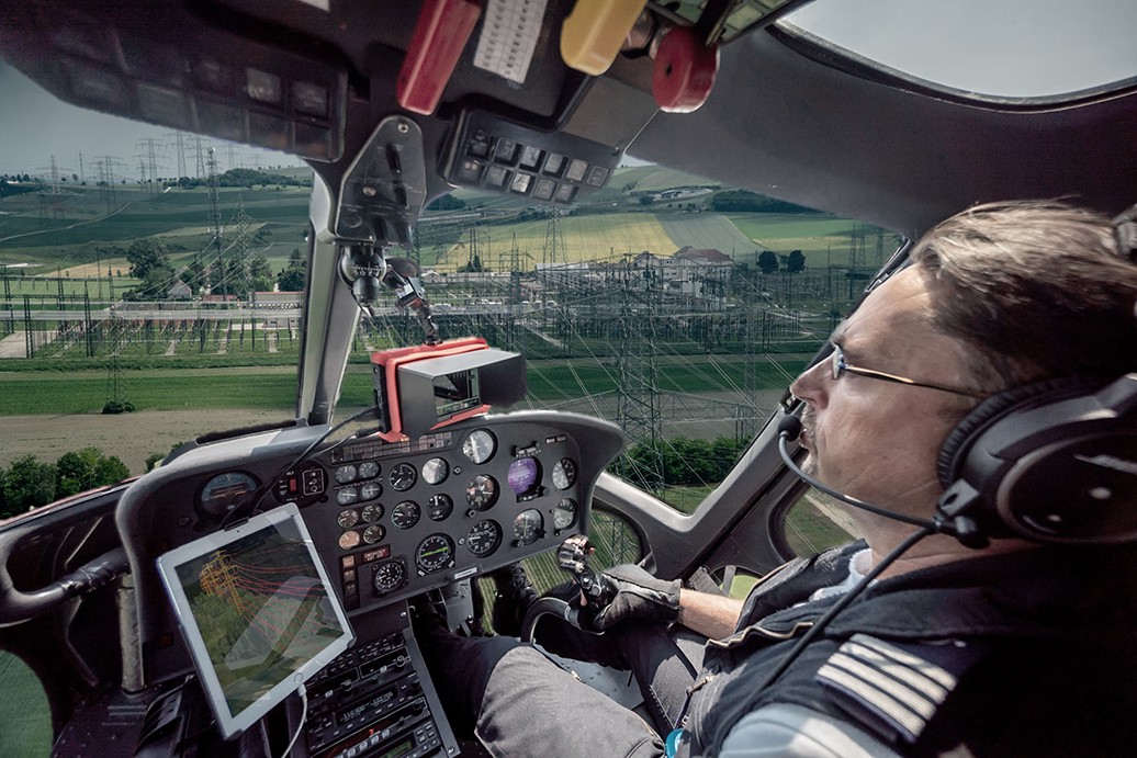 A man piloting a helicopter inside the cockpit.