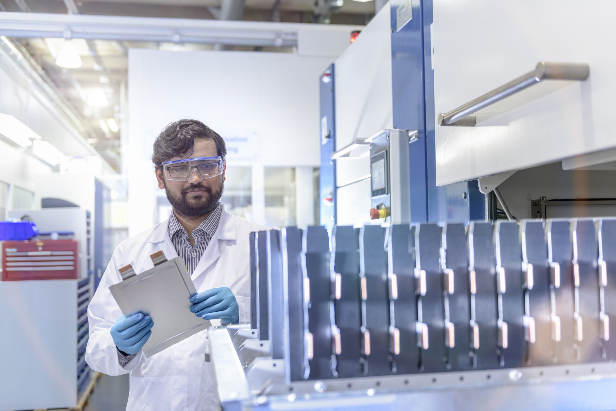 Scientist with lithium ion pouch cell manufacturing machine in battery research facility