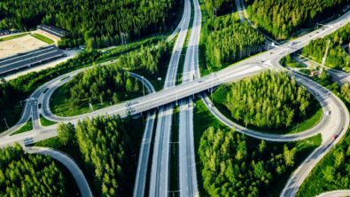A bird's eye view of a highway and its curved exit ramps in a forest.