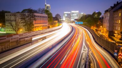 A highway through a city with continuous streams of car lights captured over time.