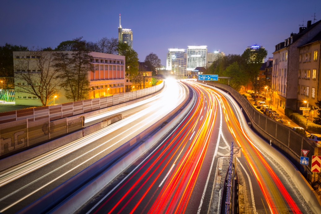 A highway through a city with continuous streams of car lights captured over time.