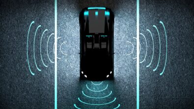 A self-driving car on a night road with imaginary sensor signals emitting from its front and sides.