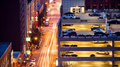 A city parking garage adjacent to a city street at night.