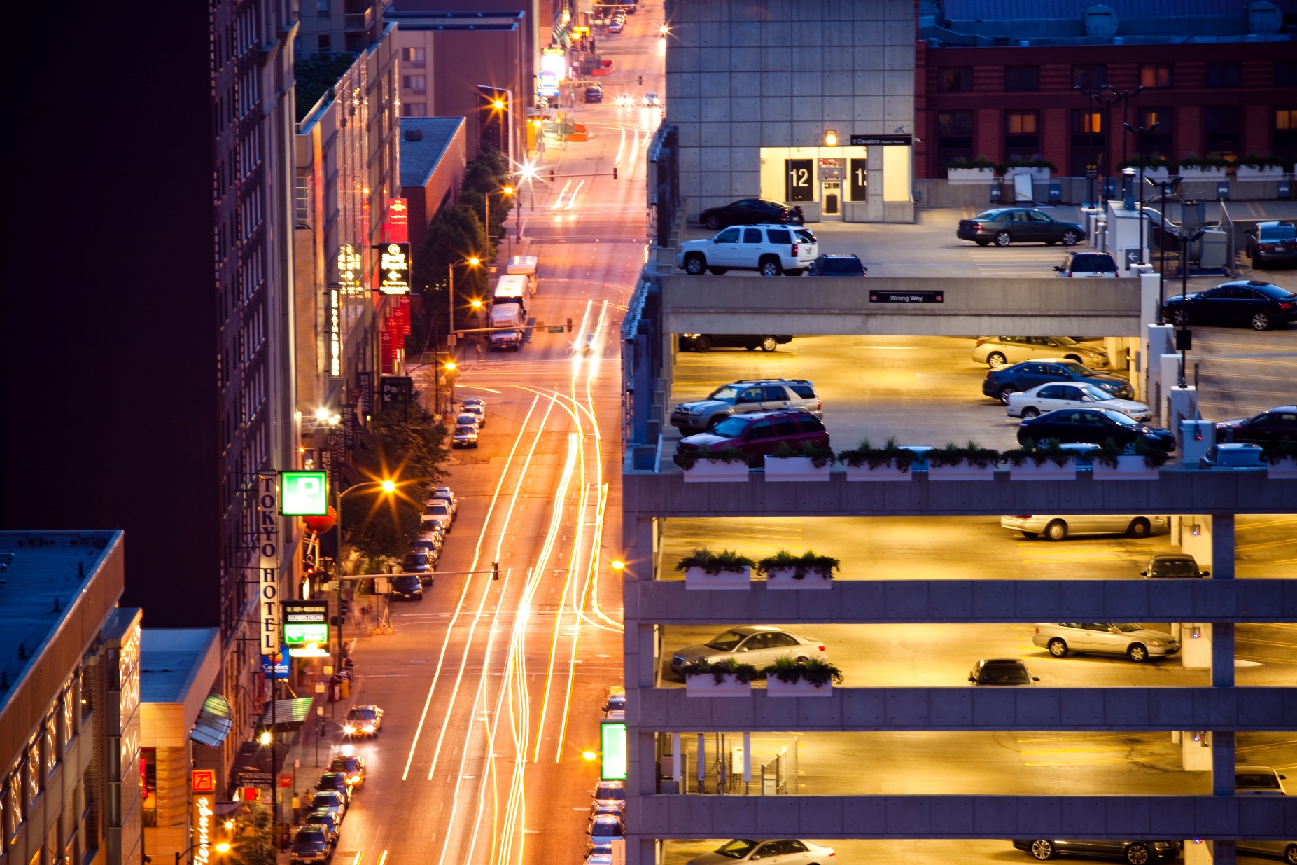 A city parking garage adjacent to a city street at night.