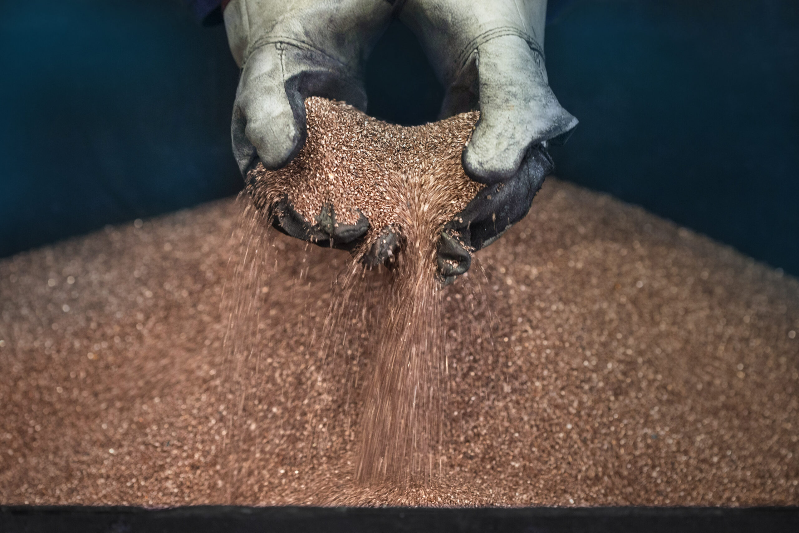 A worker handles copper shavings at a foundry.