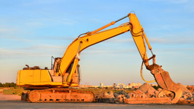 An excavator on a construction site crushing old concrete and asphalt.