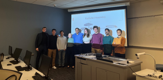 6 first-year engineering students standing in front of their final presentation with their professor and graduate teaching assistants