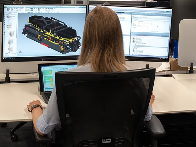 A woman on a computer with NX CAD and D-Cubed SDK open