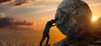 man pushing boulder uphill at sunrise