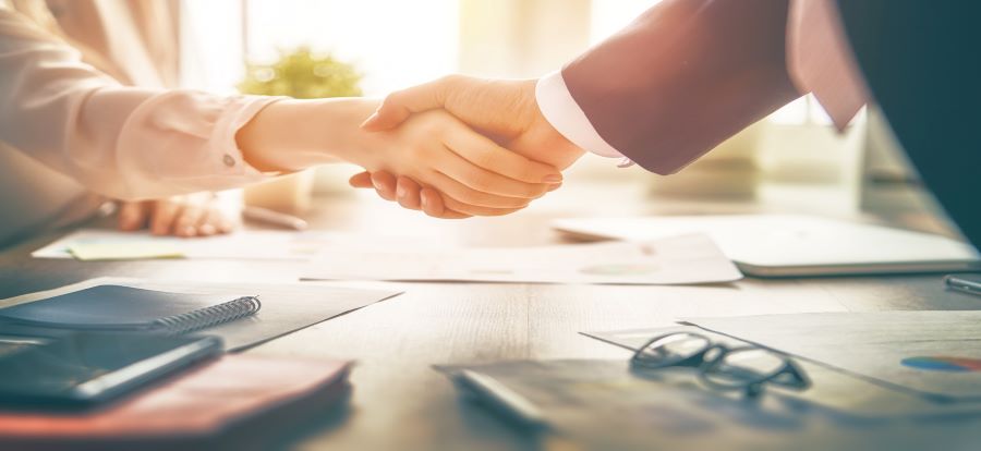 man and woman shaking hands over a conference table