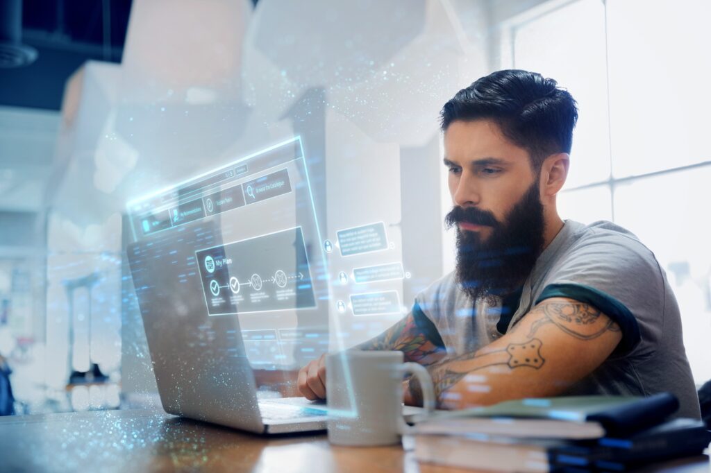 A bearded man studies a laptop screen.