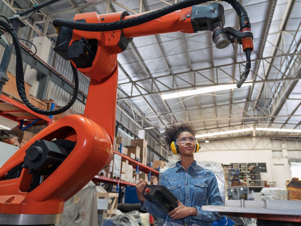 Siemens Teamcenter is part of Microsoft Cloud for Manufacturing. In this photo, a robot controls manufacturing operations while an employee looks on.