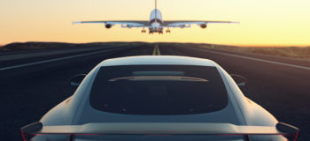 Black and gray luxury car chases airplane down stripped runway into the yellow and orange sunset. This relates to E/E Systems Development and Electrical Systems with Capital by encapsulating both the Aerospace and Automotive industry into one image as well as how we are continually moving forward with solutions for our customers.