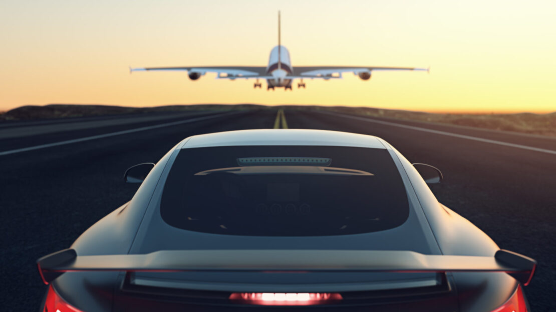 Black and gray luxury car chases airplane down stripped runway into the yellow and orange sunset. This relates to E/E Systems Development and Electrical Systems with Capital by encapsulating both the Aerospace and Automotive industry into one image as well as how we are continually moving forward with solutions for our customers. E/E Systems industry articles automotive aerospace