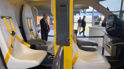 The inside of a Wisk evtol you can see four seats and the doors are open. The vehicle is yellow.