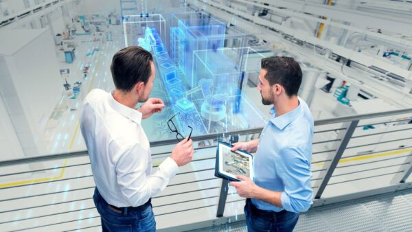 Two engineers work with new tablet technology at a manufacturing plant.