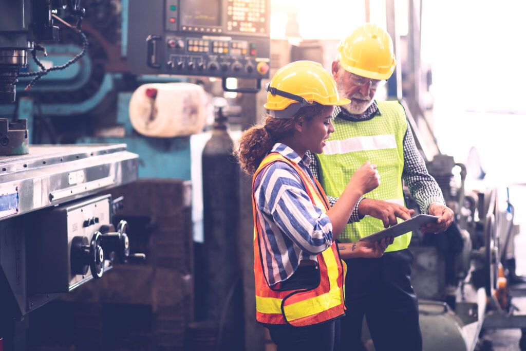 A women and a man, who are professional engineers, work together on a tablet while standing in a facitlity.