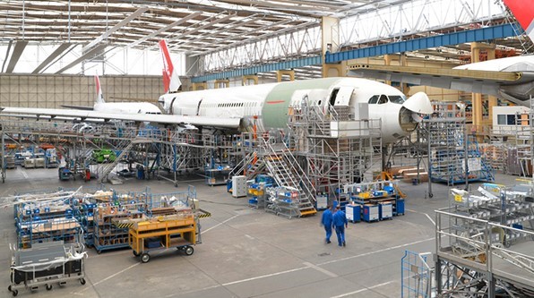 Multiple aircrafts getting built in a large airplane hangar. 