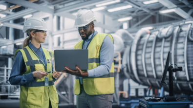 Engineers reviewing aerospace production plans on the factory floor to validate and finalize the manufacturing plan before launch.