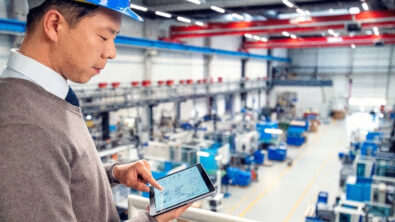 A man oversees the manufacturing floor with a computer tablet