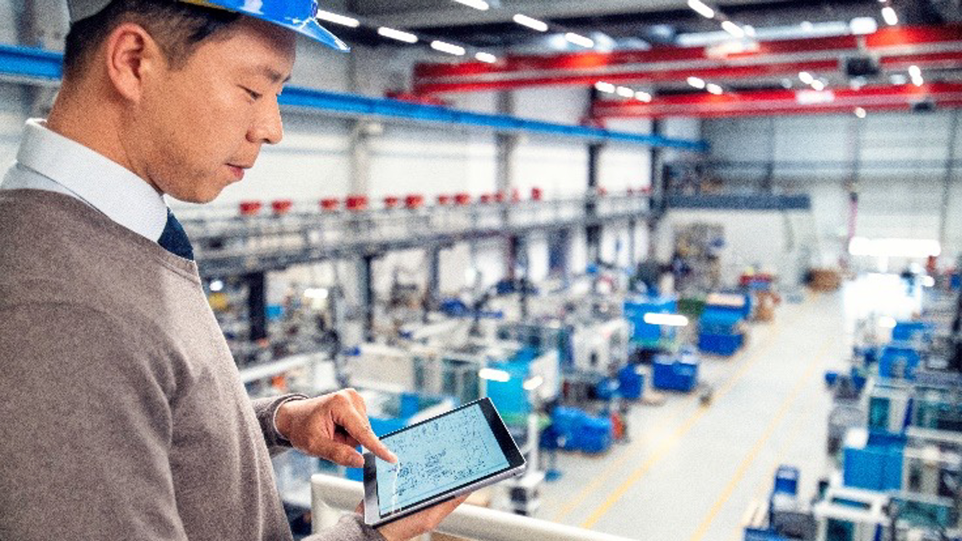 A man oversees the manufacturing floor with a computer tablet