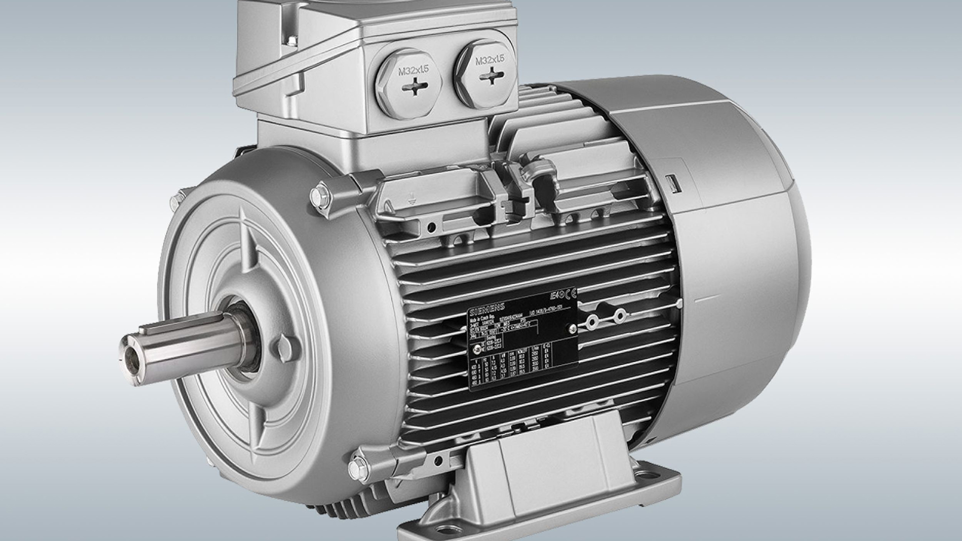 Gri bir Siemens elektrik motoru, flanş montajı ve etiketli terminallerle birlikte, gümüş bir arka plan üzerinde gösterilmiştir.