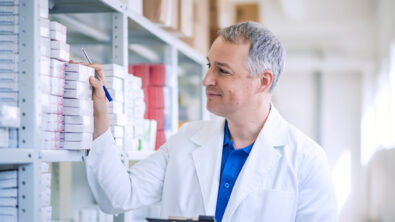 A medical professional looking at a stack of boxed medication.