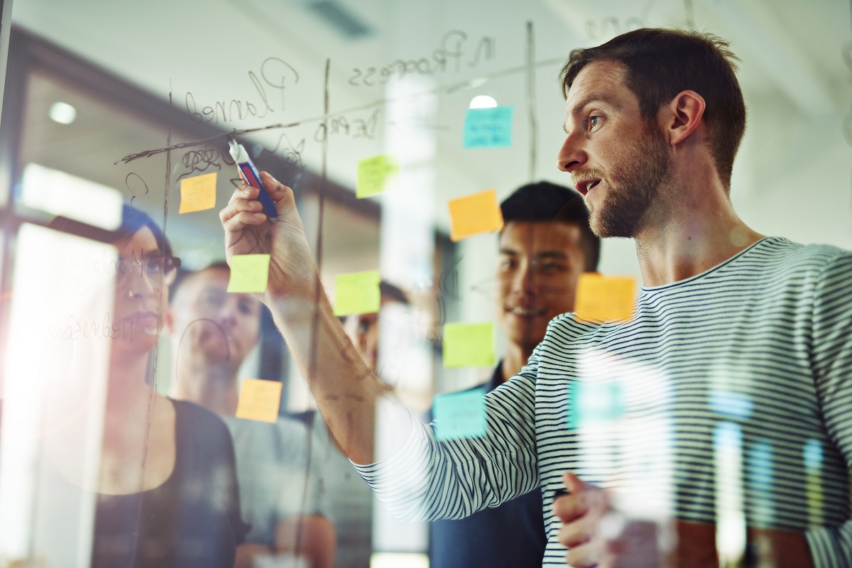 Man at glass whiteboard explaing APQP processes to team