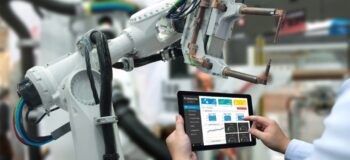 engineer using tablet with manufacturing operations management software to interface with robot arm in a smart factory