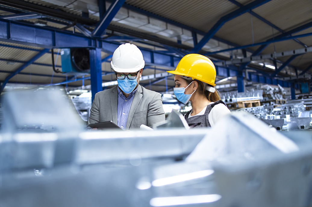 Working people with protection mask during corona virus pandemic. Industrial supervisor manager with hygienic mask controlling workers in production factory.