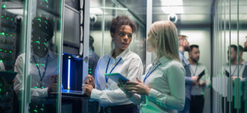 Two women in a server room discussing MES and ERP systems