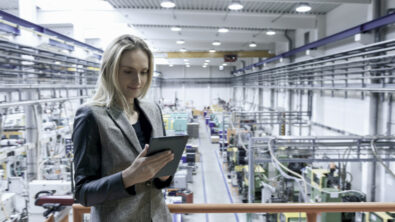 Woman using a tablet PC and standing in front of a production line
