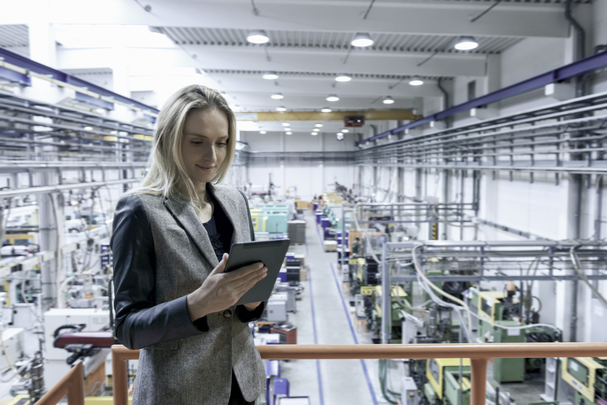 Woman using a tablet PC and standing in front of a production line