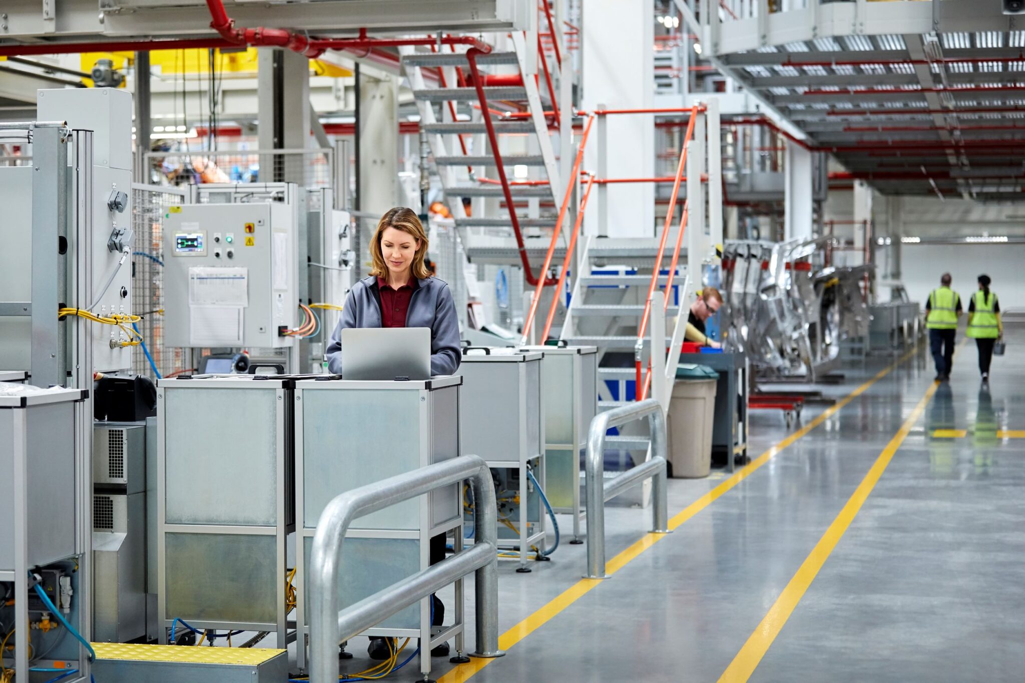 Woman at a standing computer terminal in the middle of a manufacturing plant