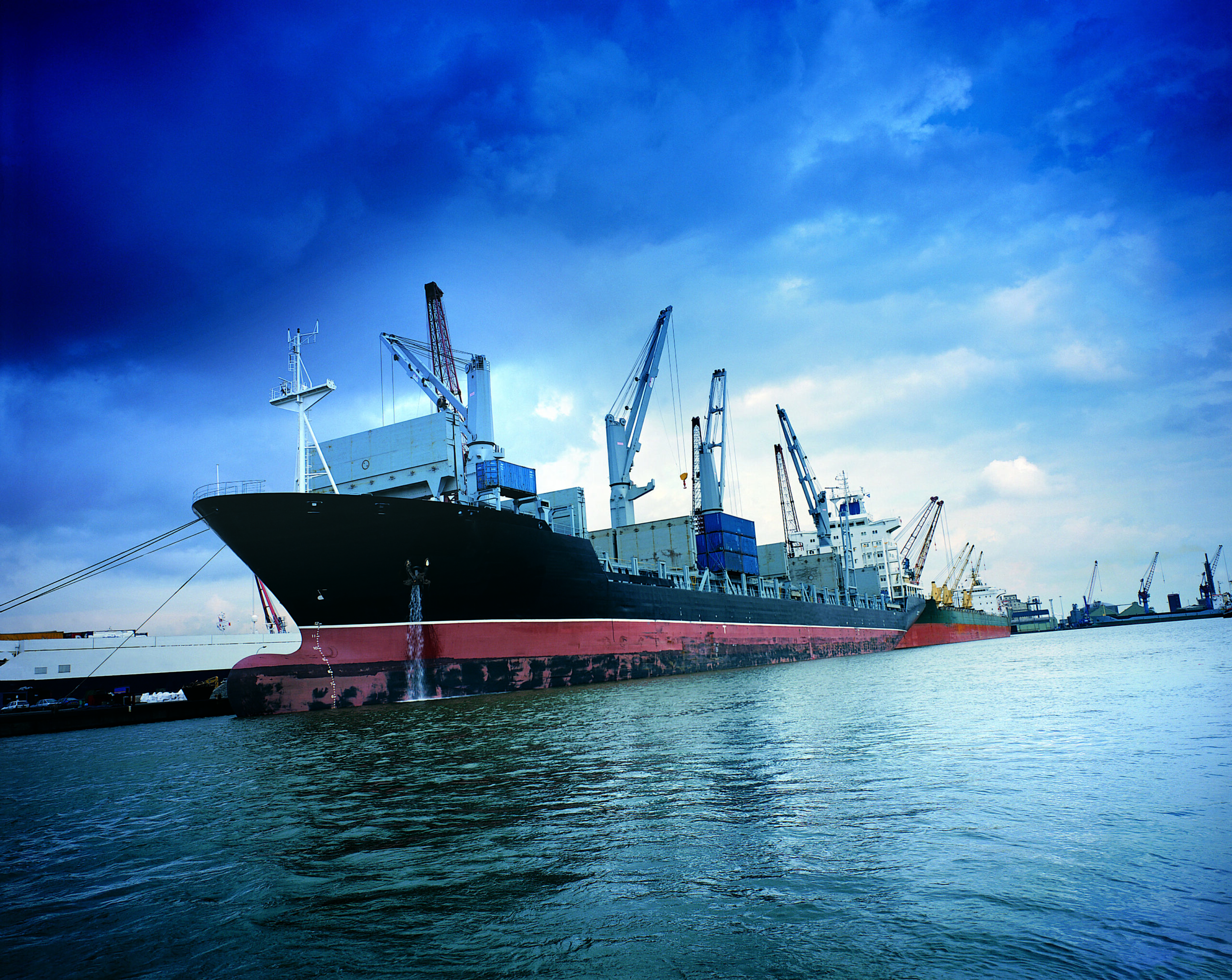 A container ship getting loaded with cargo at a harbor.