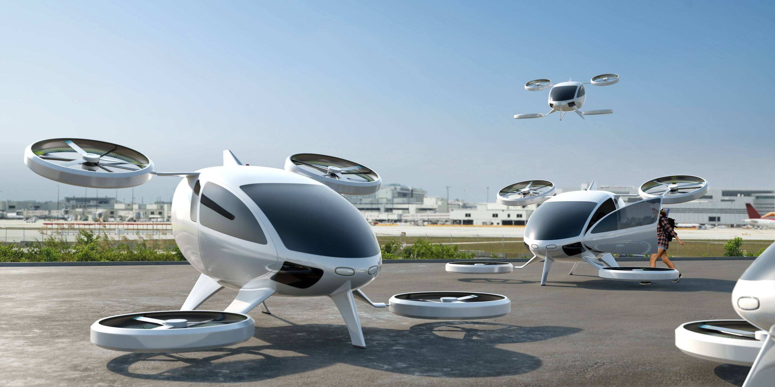 A concept image of three advanced air mobility vehicles landed at an airport, and another flying in the air.