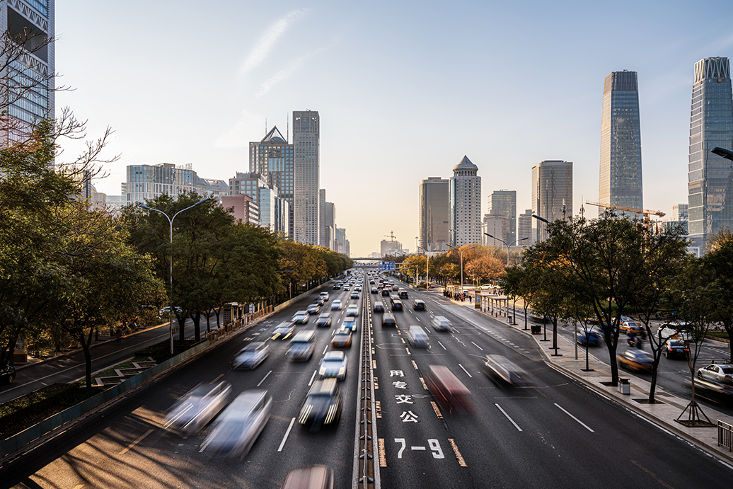 A busy highway filled with cars driving in both directions through a city.