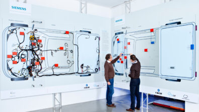 Two employees mapping the electrical architecture of a vehicle on interactive white boards