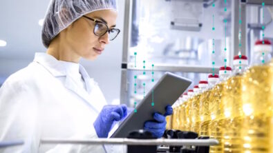 Woman with tablet doing quality inspection at a production line with bottles